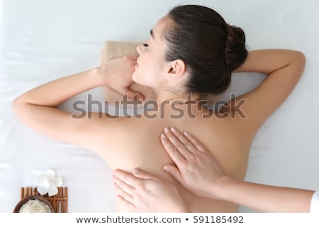 Foto stock: Young Woman Relaxing On Massage Table In Health Spa With Flower