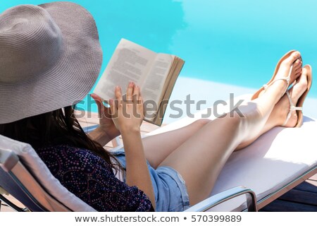 Foto stock: Caucasian Woman Sunbathing And Reading Book