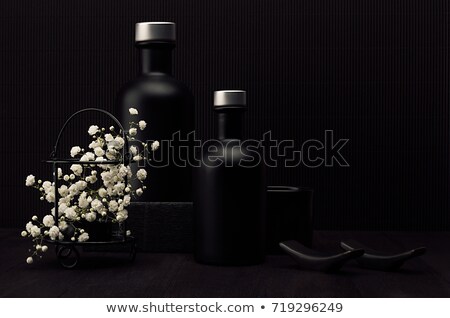 Stock photo: Noir Exquisite Home Decor With Blank Black Cosmetics Bottles White Small Flowers On Dark Wood Board