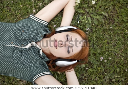Foto stock: Beautiful Red Haired Girl At Grass With Headphones