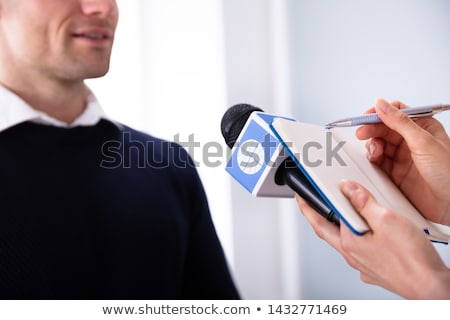 Foto stock: Journalist Writing On Diary While Taking An Interview