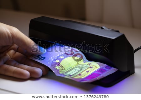 Foto stock: Person Checking Banknote Through The Currency Detector