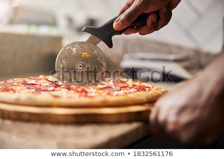 Stok fotoğraf: Fresh Round Baked Pepperoni Italian Pizza With Wheel Cutter And Knife With Tomatoes And Basil On Bla