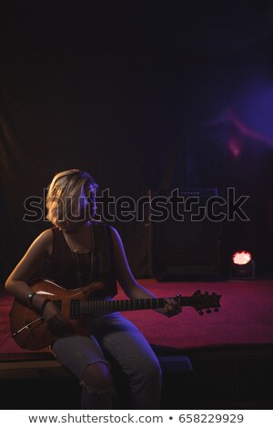 Foto stock: Female Guitarist Playing Guitar While Sitting On Stage