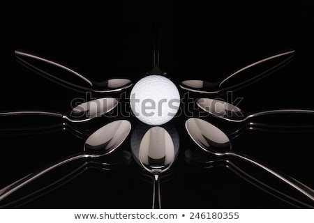 Stock fotó: Teaspoons And White Golf Ball On The Black Glass Table