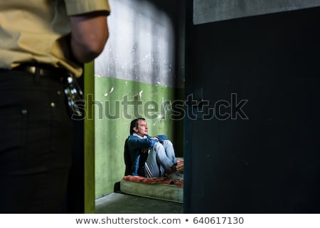 Foto stock: Young Male Prisoner Sitting Alone In An Obsolete Prison Cell Gua