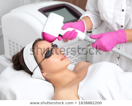 Foto stock: Doctor Waxing Womans Forehead