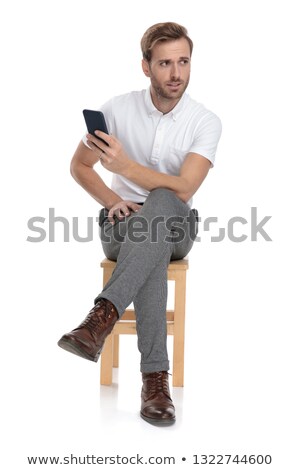 Foto stock: Seated Casual Man Texting On His Phone And Looks Away