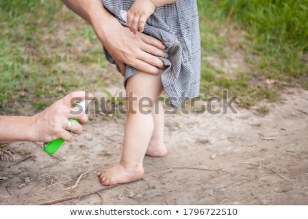 Foto d'archivio: Dad And Son Use Mosquito Sprayspraying Insect Repellent On Skin Outdoor