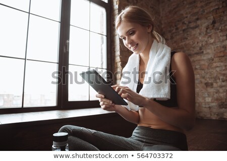 Stockfoto: Fitness Lady With Towel Sitting In Gym While Using Tablet