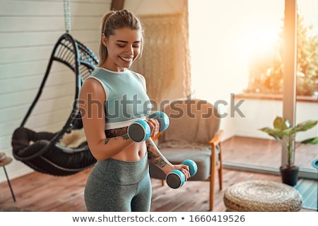 Stockfoto: Young Woman Exercising With Dumbbells In Gym