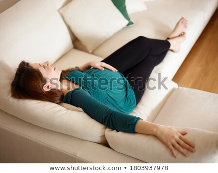 [[stock_photo]]: Mid Adult Woman Expecting Baby Lying On Sofa