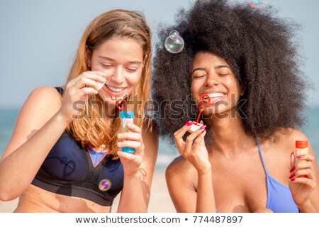 Stock foto: Young Women Or Girls Blowing Bubbles On Beach