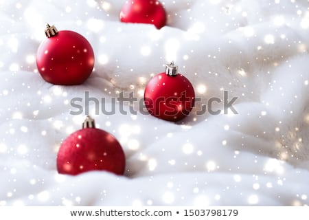 Foto d'archivio: Red Christmas Baubles On Fluffy Fur With Snow Glitter Luxury Wi