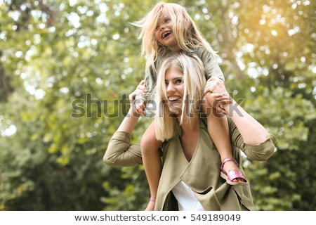 Stock photo: Daughter Sits At Mother On Back In Spring Park