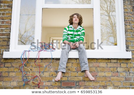 Сток-фото: Teenage Boy Sat On Windowsill
