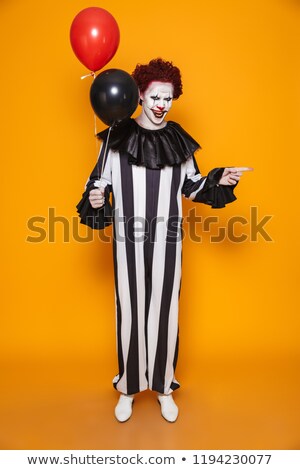 Stock photo: Creepy Man Clown Holding Balloons And Pointing At Copy Space