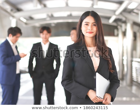 Stok fotoğraf: Front View Of Beautiful Asian Businesswoman Holding And Looking At Laptop While Sitting In The Audit