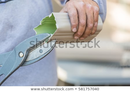 Foto stock: Worker Cutting Aluminum Rain Gutter With Heavy Shears