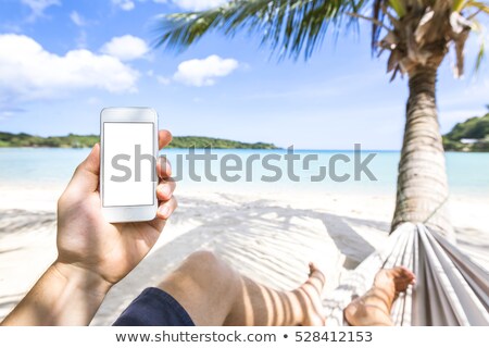 Foto stock: Male Hand With Mobile Phone On The Beach