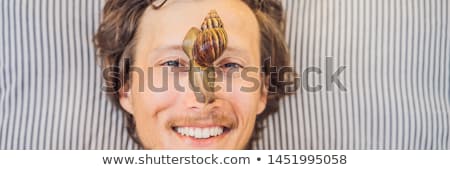 Stok fotoğraf: Young Man Makes A Face Mask With Snail Mucus Snail Crawling On A Face Mask Spa For Man Spa For Al