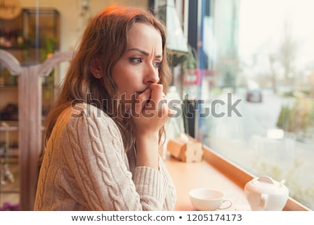 Stockfoto: Nervous Woman Biting Nails And Looking Away Sitting Alone In A Coffee Shop