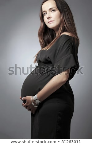 Foto stock: Stómago · de · la · mujer · embarazada · sobre · un · fondo · oscuro