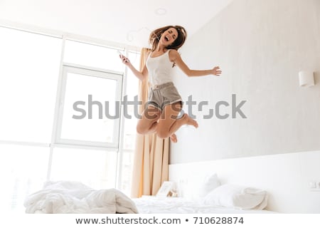 Stockfoto: Happy Young Woman With Smartphone In Bed At Home