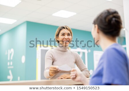 Stock foto: Young Cheerful Patient Giving Medical Paper To Receptionist Or Clinician
