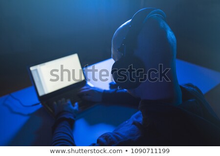 Stok fotoğraf: Hacker In Headset Typing On Laptop In Dark Room