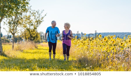 Foto stock: Two Healthy Senior People Jogging On A Country Road In Summer