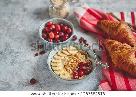 Stockfoto: Ceramic Bowl Of Oatmeal Porridge With Banana Fresh Cranberries And Walnuts