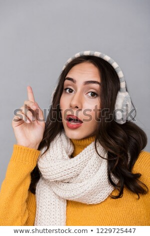 Stok fotoğraf: Portrait Of Excited Woman Wearing Ear Muffs And Scarf Pointing F