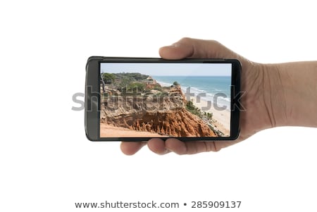 Stok fotoğraf: Female Hand With Mobile Phone Algarve Cliffs