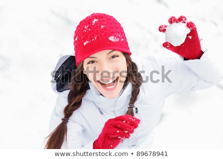 Foto stock: Winter Girl Throwing Snowball At Camera Smiling Happy Having Fun Outdoors On Snowing Winter Day Play