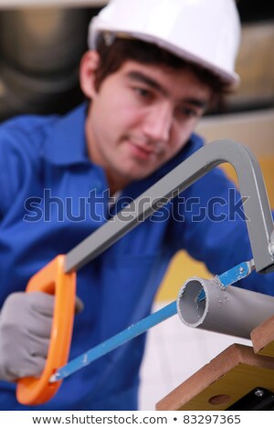 Foto d'archivio: Young Man Is Cutting A Pvc Pipe With A Saw