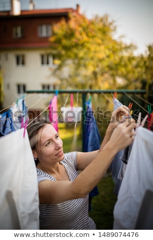 Foto stock: Young Woman Putting Laundry On A Rope In Her Garden