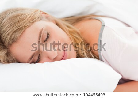 Stock fotó: A Woman Lying In Bed As She Rests Her Head On A Pillow Here Eyes Are Closed