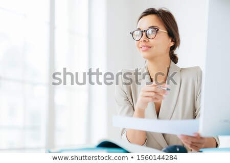 Foto stock: Photo Of Thoughtful Brunette Woman In Formal Wear Spectacles Holds Pen And Paper Looks Pensively