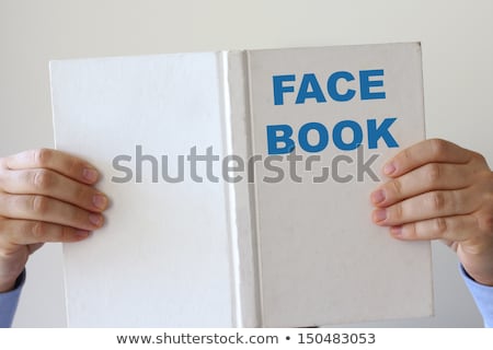 Foto stock: Man Reading A Book Entitled Face Book