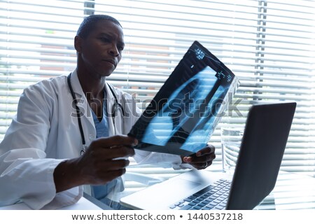 Foto d'archivio: Surgeon Sitting At Window And Checking X Ray