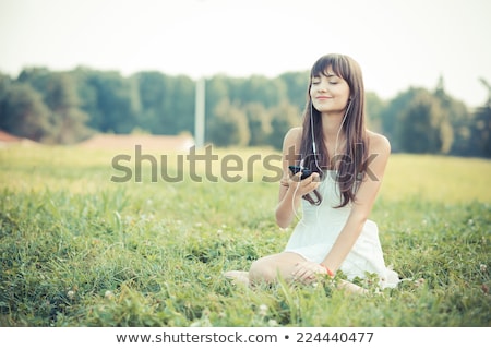 Stock fotó: Woman Listening To Music On Smartphone At Park