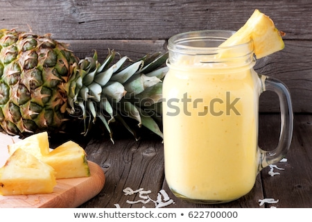 Stock fotó: Pineapple And Pineapple Smoothies Against The Background Of A Branch Of A Palm Tree