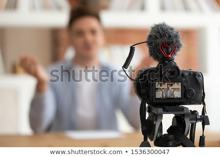 Stok fotoğraf: Screen Of Video Camera In Front Of Young Male Vlogger Sitting By Desk