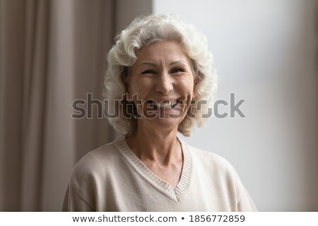 Foto stock: Candid Shot Of Good Looking Lady With Curly Hairstyle Smiles Cute Keeps Both Hands On Cheeks Show