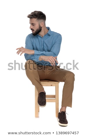 ストックフォト: Casual Man Sitting On A Stool Looks Away To Side