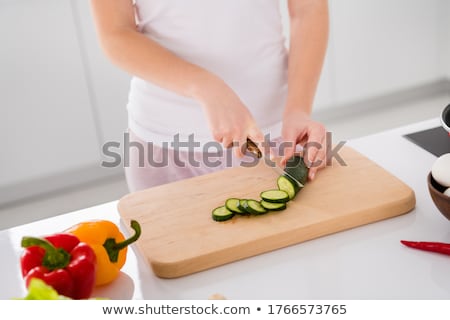 Foto stock: Woman Slicing Cucumber With Kitchen Knife