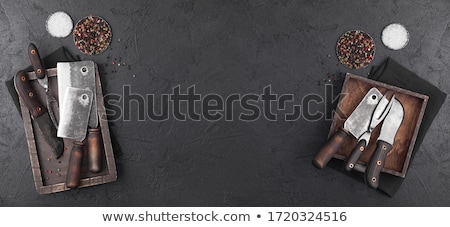 Foto d'archivio: Vintage Meat Knife And Fork And Hatchets With Stone Chopping Board And Black Table Background Butch