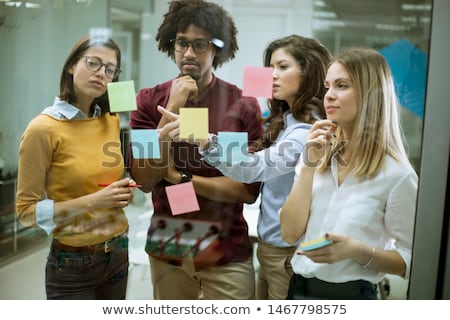 Foto stock: Young Business People Discussing In Front Of Glass Wall Using Po