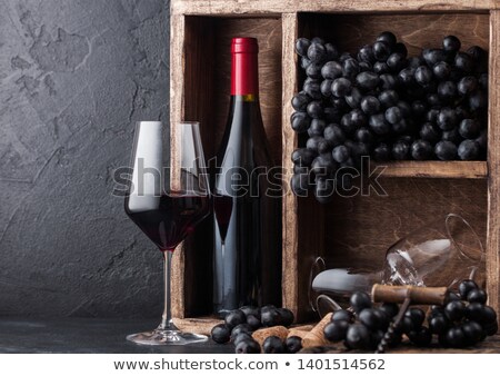 Stock fotó: Bottle Of Red Wine With Dark Grapes And Corks Inside Vintage Wooden Box On Black Stone Background N